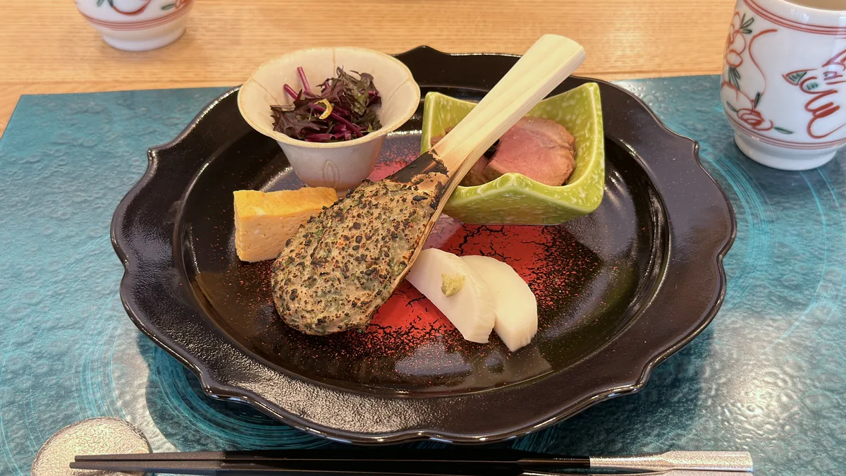 黒い稜花の皿に前菜を盛り付けた、蕎席 雅山の開店時の器